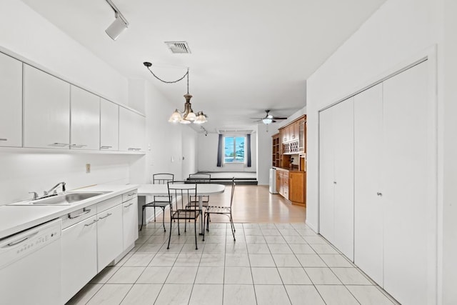 kitchen featuring decorative light fixtures, light countertops, visible vents, white dishwasher, and a sink