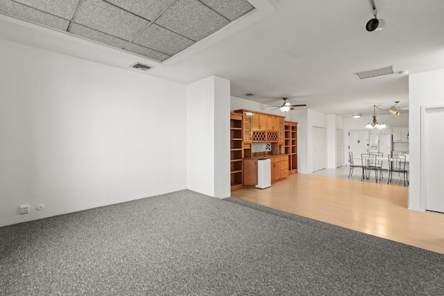 unfurnished living room featuring visible vents, wood finished floors, carpet flooring, and ceiling fan with notable chandelier