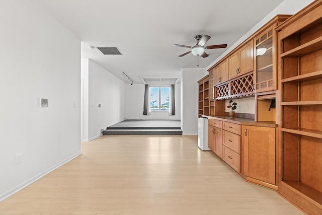 kitchen with glass insert cabinets, light wood-style floors, brown cabinets, open shelves, and rail lighting