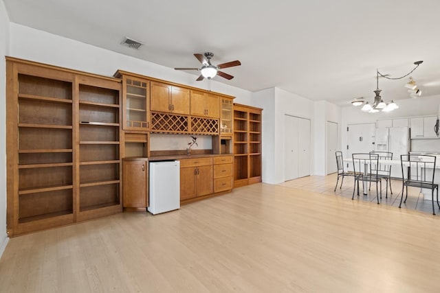 interior space with refrigerator, white refrigerator with ice dispenser, open shelves, visible vents, and brown cabinetry