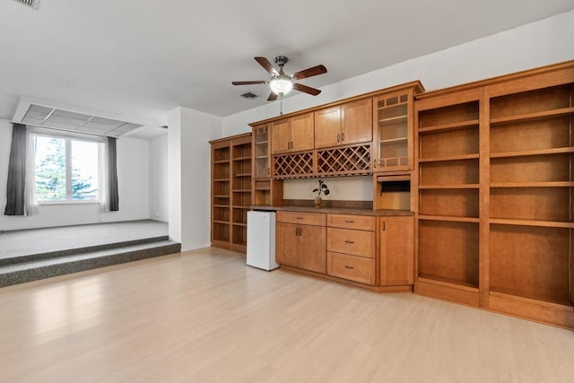 interior space with a ceiling fan, visible vents, and light wood finished floors