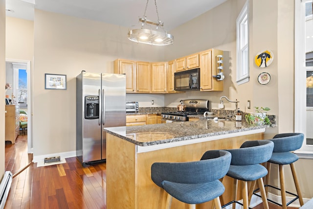 314 Palisade Ave Unit 3, Jersey City, NJ 07307 - kitchen featuring stainless steel appliances, light brown cabinetry, a sink, dark stone counters, and a peninsula