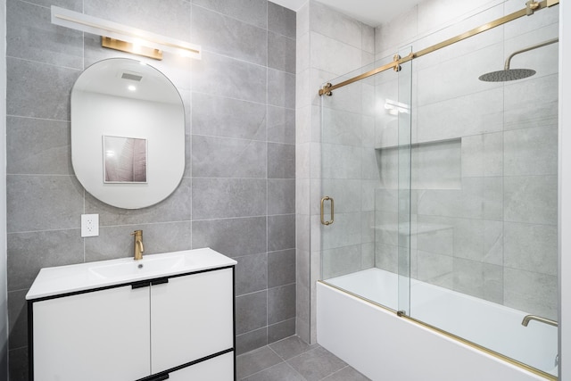 bathroom featuring shower / bath combination with glass door, vanity, tile patterned floors, and tile walls