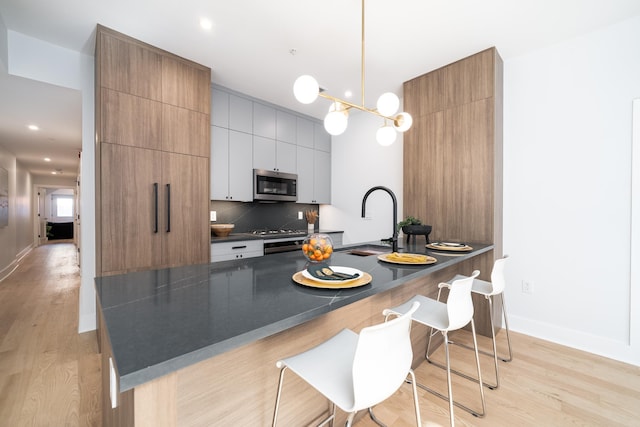 kitchen featuring tasteful backsplash, white cabinetry, hanging light fixtures, and light hardwood / wood-style floors