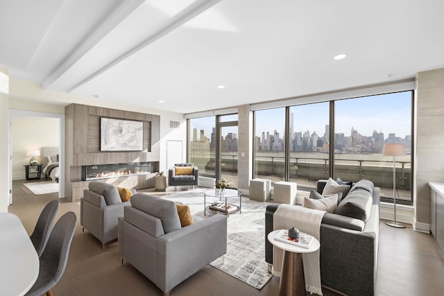 living room featuring wood-type flooring, a wall of windows, and a large fireplace