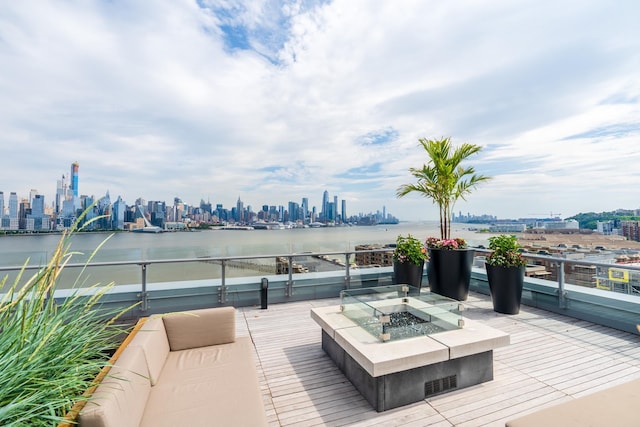 wooden terrace with a water view and an outdoor fire pit