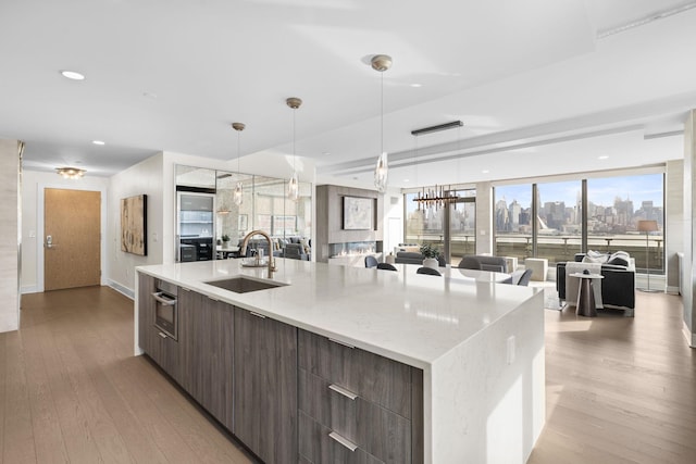 kitchen with hanging light fixtures, light hardwood / wood-style flooring, a spacious island, and sink