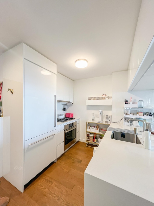 99 Hudson St Unit 2912, Jersey City, NJ 07302 - kitchen featuring oven, a sink, white cabinets, and light wood-type flooring