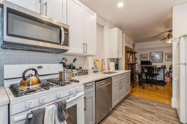 kitchen featuring tasteful backsplash, appliances with stainless steel finishes, light countertops, and a sink