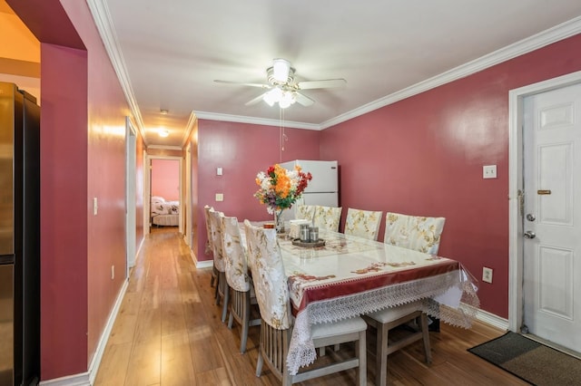 dining room featuring ceiling fan, hardwood / wood-style flooring, baseboards, and ornamental molding