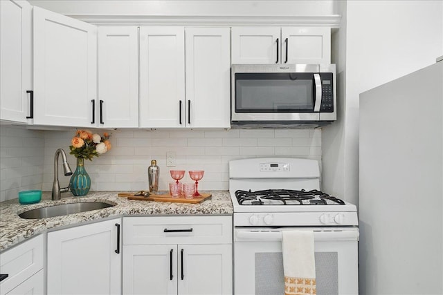 144 Nelson Ave, Jersey City, NJ 07307 - kitchen with stainless steel microwave, white gas stove, a sink, white cabinetry, and backsplash