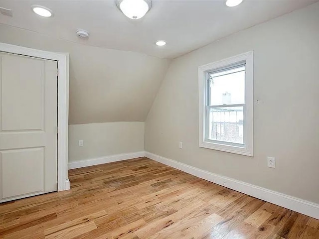 additional living space with recessed lighting, lofted ceiling, light wood-type flooring, and baseboards