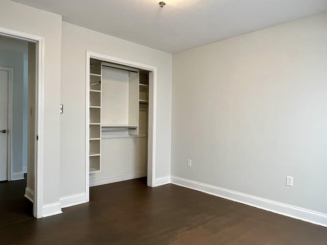 unfurnished bedroom with dark wood-style floors, a closet, and baseboards