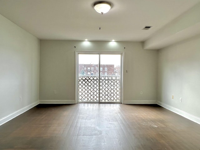 unfurnished room with dark wood-type flooring, visible vents, and baseboards