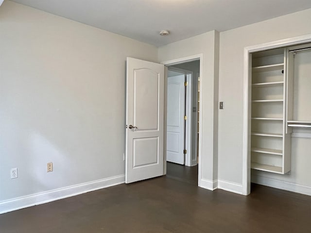 unfurnished bedroom with concrete flooring, a closet, and baseboards