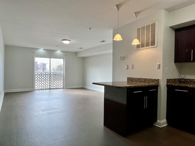 kitchen featuring baseboards, visible vents, open floor plan, dark stone countertops, and hanging light fixtures