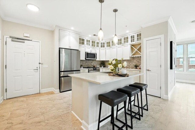 126 Dudley St Unit 315, Jersey City, NJ 07302 - kitchen featuring appliances with stainless steel finishes, crown molding, decorative backsplash, glass insert cabinets, and a breakfast bar