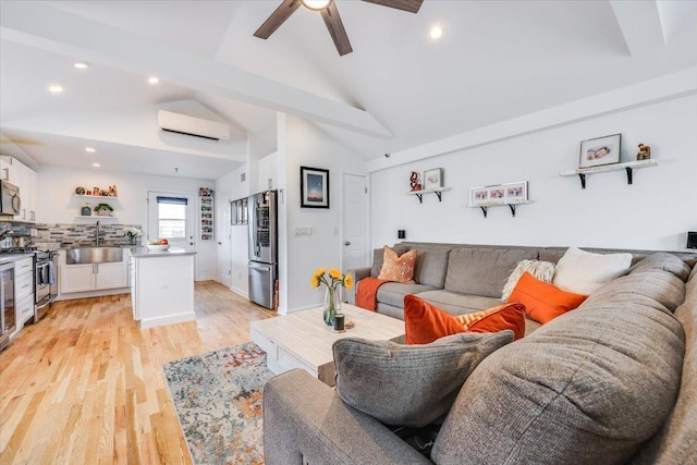 living room with sink, vaulted ceiling, an AC wall unit, ceiling fan, and light hardwood / wood-style floors