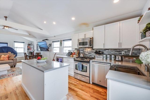 kitchen featuring sink, white cabinetry, a center island, vaulted ceiling, and appliances with stainless steel finishes