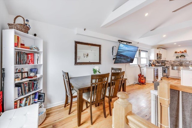 dining room with light hardwood / wood-style flooring, sink, and vaulted ceiling