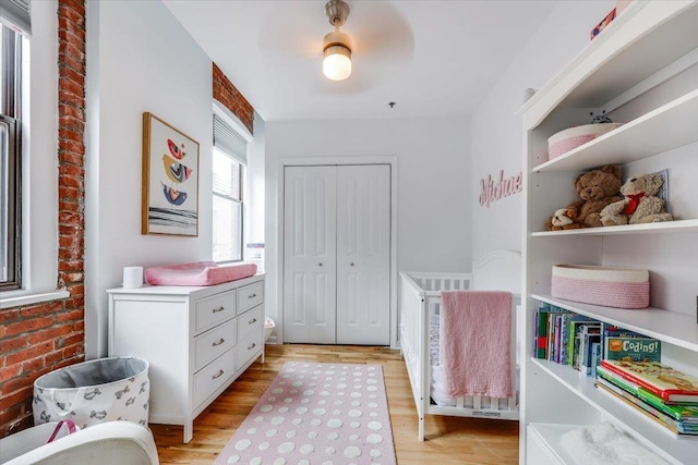 bedroom with ceiling fan, brick wall, a closet, and light wood-type flooring