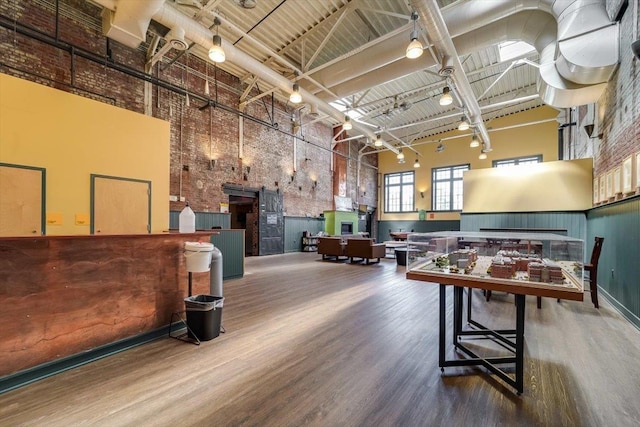 recreation room featuring hardwood / wood-style flooring, rail lighting, and a towering ceiling