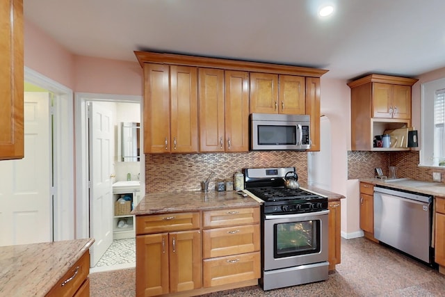 kitchen featuring stainless steel appliances, backsplash, and light stone countertops