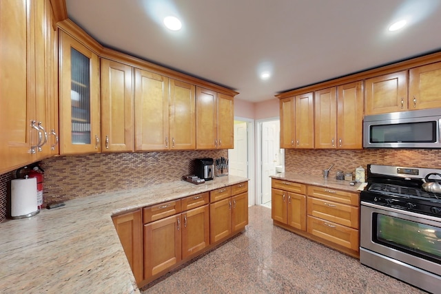 kitchen with stainless steel appliances, decorative backsplash, and light stone counters