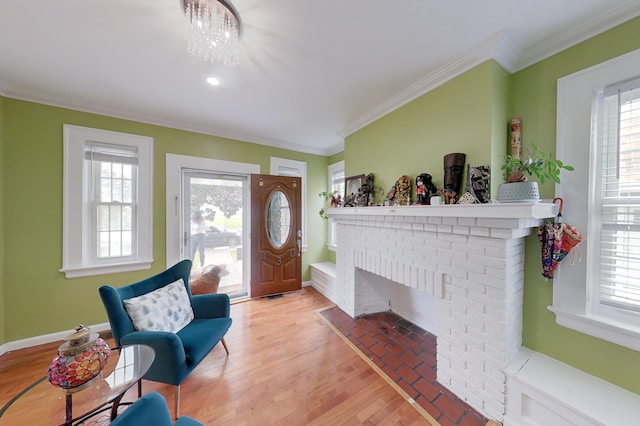 foyer featuring a fireplace, light wood-type flooring, crown molding, and plenty of natural light