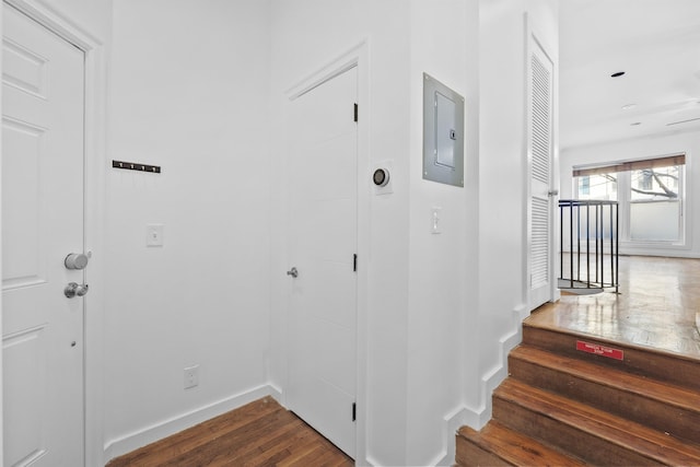 stairs with electric panel and hardwood / wood-style flooring