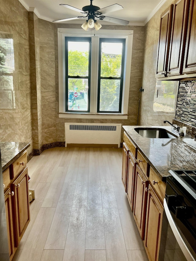 108 Palisade Ave Unit A5, Jersey City, NJ 07306 - kitchen featuring radiator, crown molding, dark stone countertops, a ceiling fan, and brown cabinetry