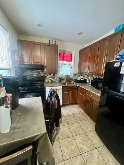 kitchen with light tile patterned floors, backsplash, a sink, under cabinet range hood, and black appliances