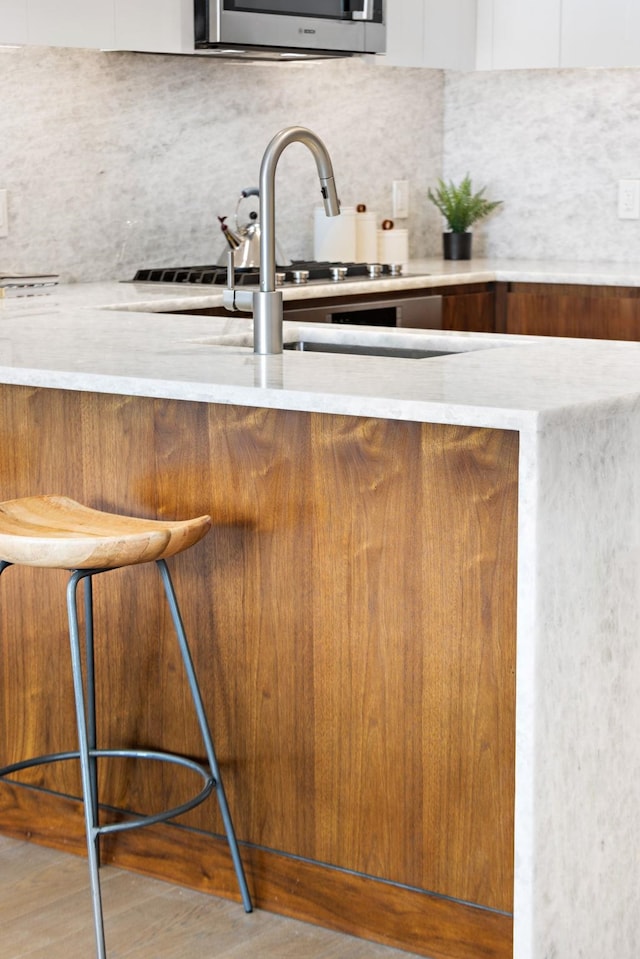 kitchen featuring hardwood / wood-style floors, tasteful backsplash, a breakfast bar area, and sink