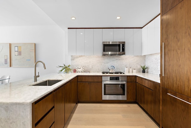 kitchen featuring white cabinets, stainless steel appliances, sink, and light hardwood / wood-style flooring