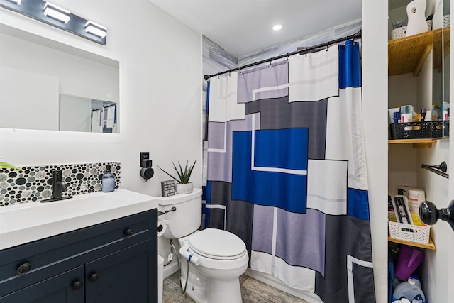 bathroom featuring vanity, toilet, walk in shower, and tasteful backsplash