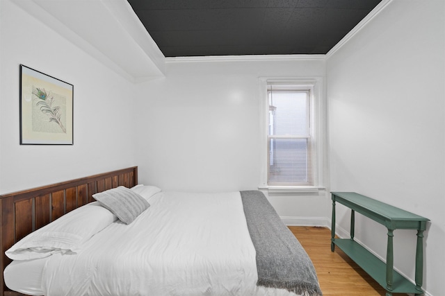 bedroom with crown molding, baseboards, and wood finished floors