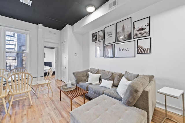 living room featuring visible vents, baseboards, and wood finished floors