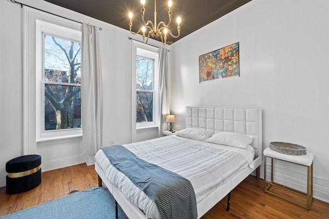 bedroom with multiple windows, wood finished floors, and a notable chandelier