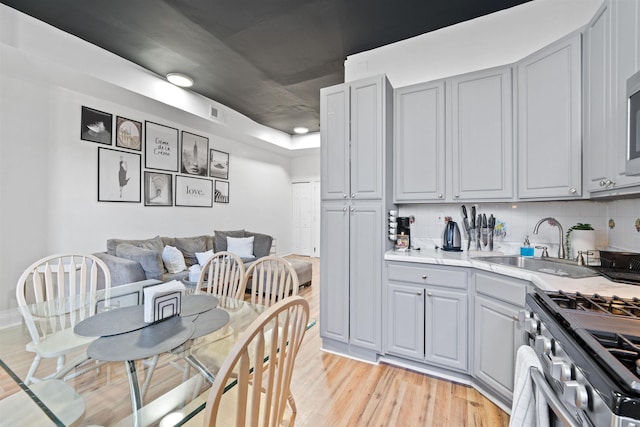 kitchen featuring light wood-style flooring, gray cabinetry, and gas stove