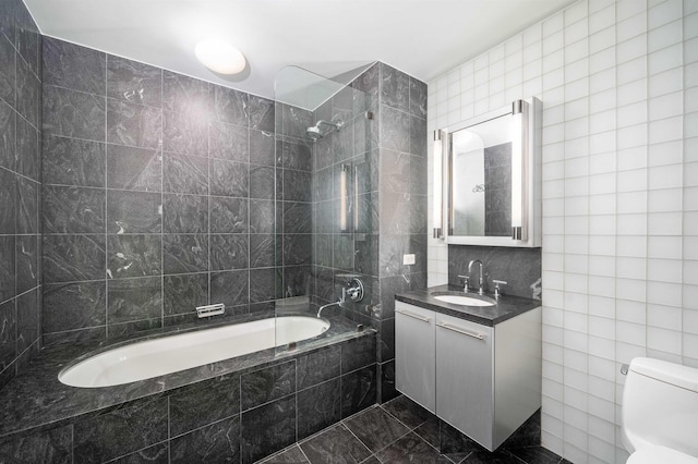 full bathroom with tiled shower / bath combo, toilet, tile walls, and vanity