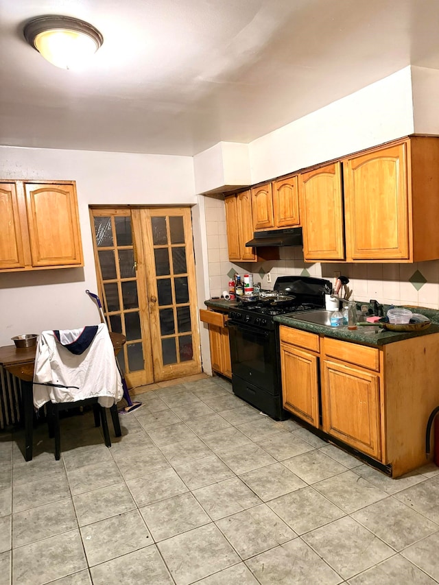 kitchen featuring black gas stove, light tile patterned floors, and decorative backsplash