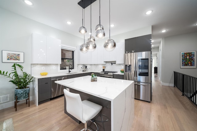 kitchen featuring white cabinetry, a center island, stainless steel appliances, tasteful backsplash, and pendant lighting