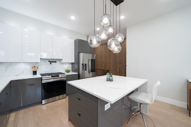 kitchen with white cabinetry, a center island, hanging light fixtures, stainless steel appliances, and tasteful backsplash