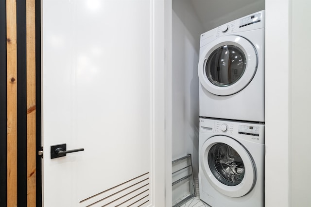 laundry room featuring stacked washer / dryer and light tile patterned flooring