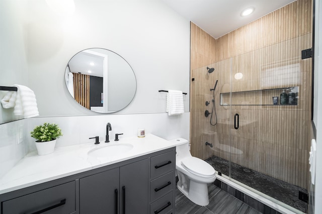 bathroom featuring vanity, tasteful backsplash, toilet, and a shower with door