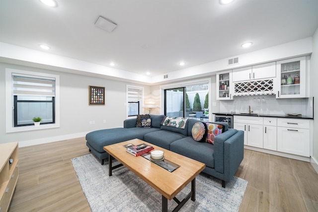 living room with wet bar, wine cooler, and light hardwood / wood-style flooring