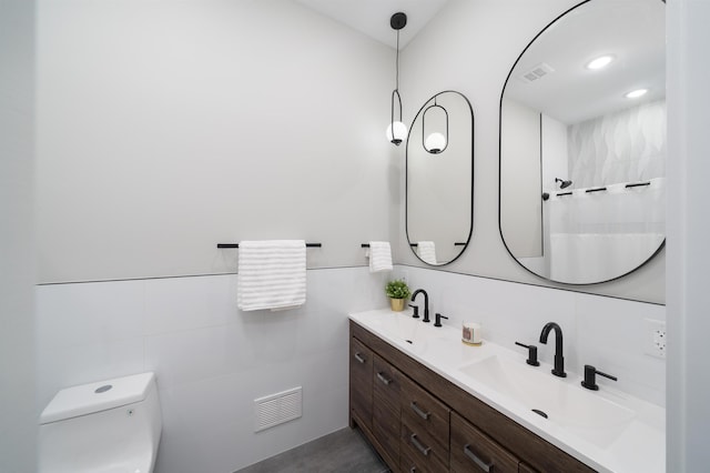 bathroom featuring vanity, toilet, and tile walls