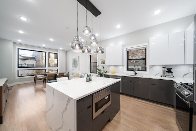 kitchen featuring appliances with stainless steel finishes, sink, pendant lighting, white cabinets, and a center island