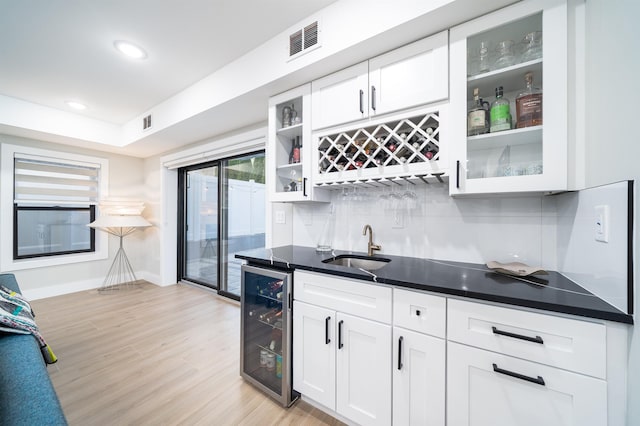 interior space with white cabinets, light hardwood / wood-style floors, wine cooler, and sink