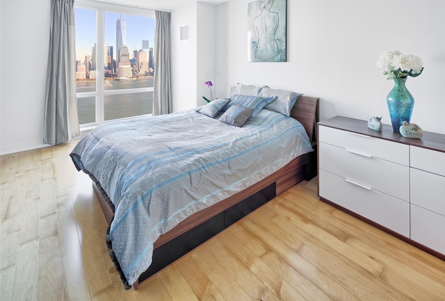 bedroom with a view of city, visible vents, and light wood-style floors